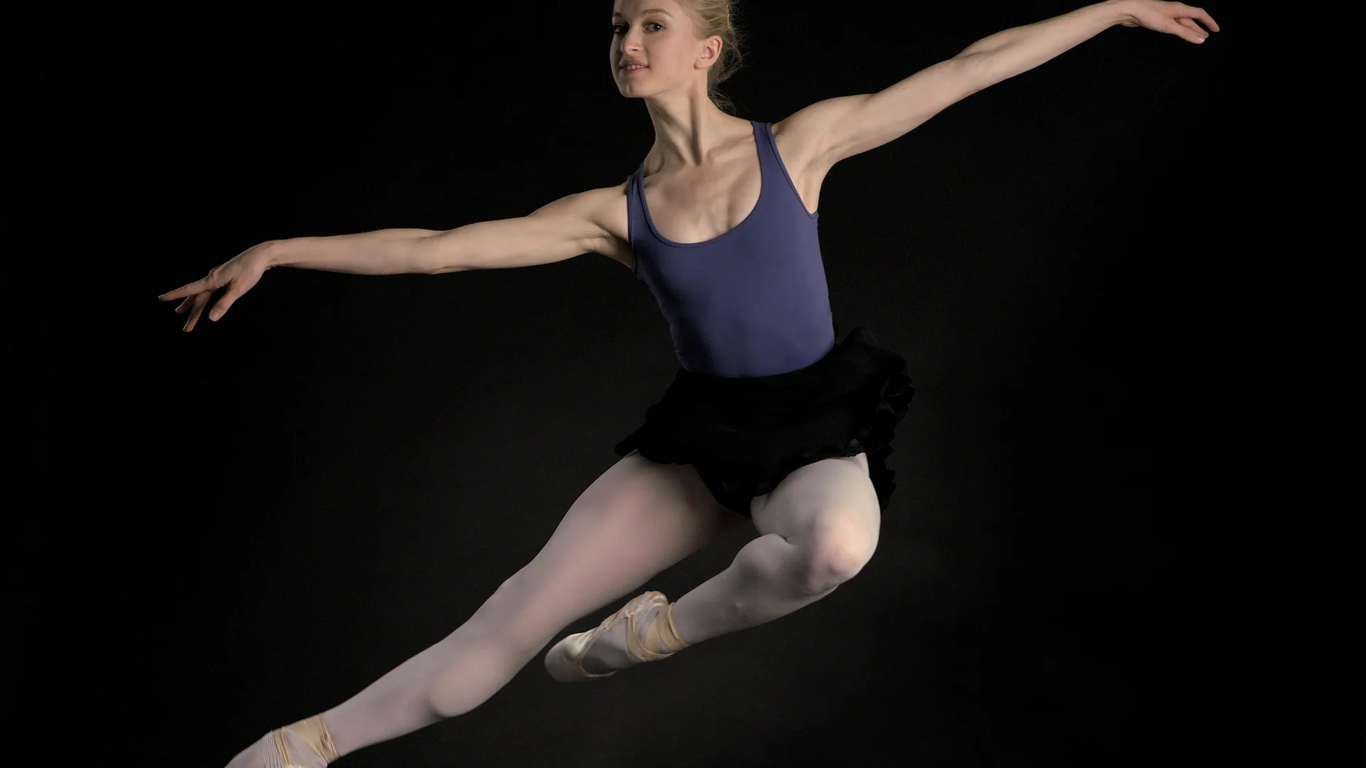 A dancer mid-jump against a black background, illustrative of a BalletX premiere