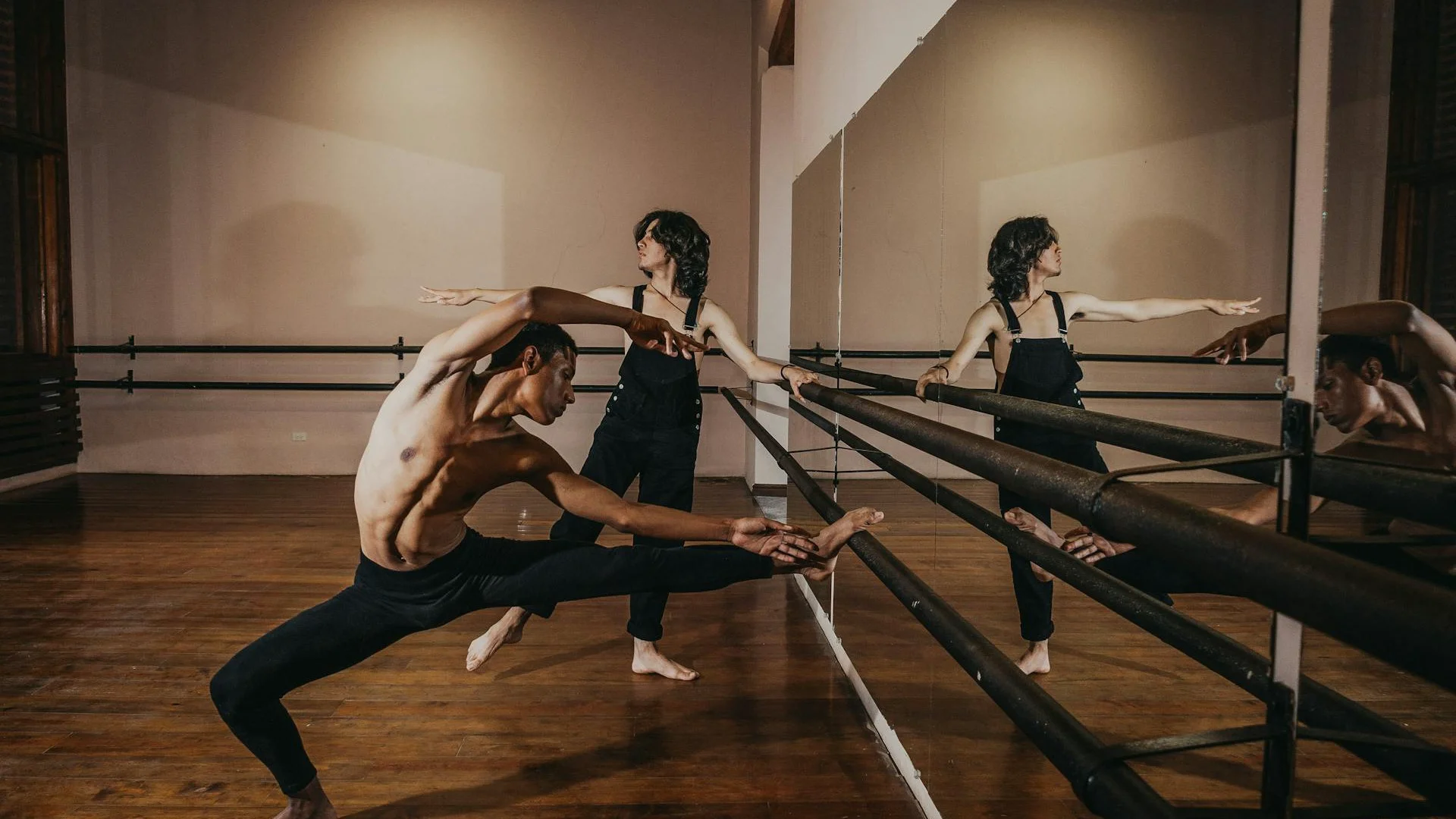 Two dancers rehearsing at a studio barre, illustrative of Nederlands Dans Theater's rigorous contemporary training