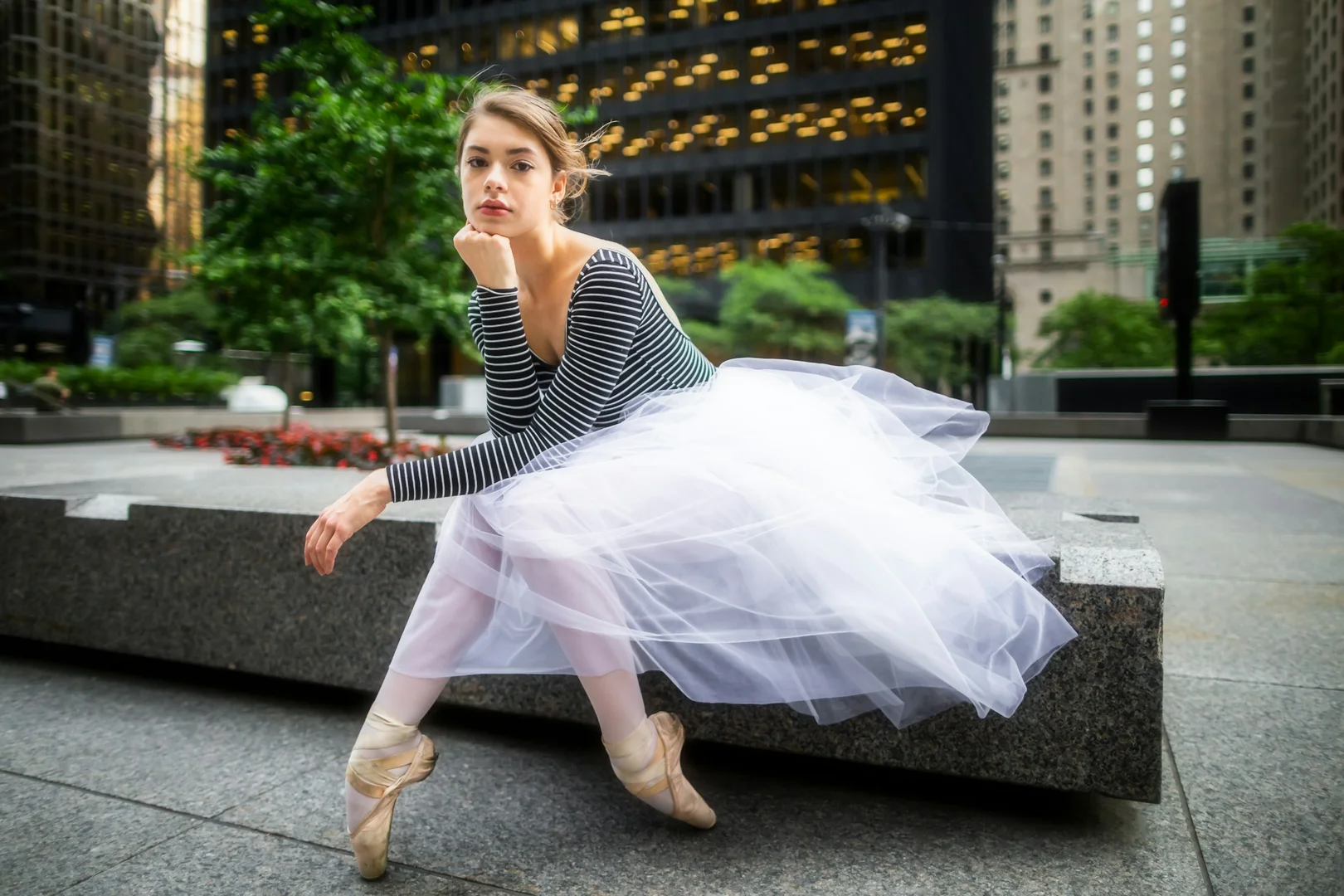 A dancer in a tutu and striped top posed starkly in an urban plaza, illustrative of Mats Ek's modern-dress, psychologically charged reimagining of Giselle